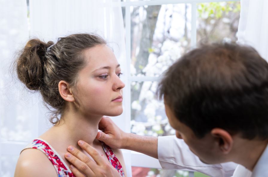 Doctor examines woman with enlarged thyroid gland.